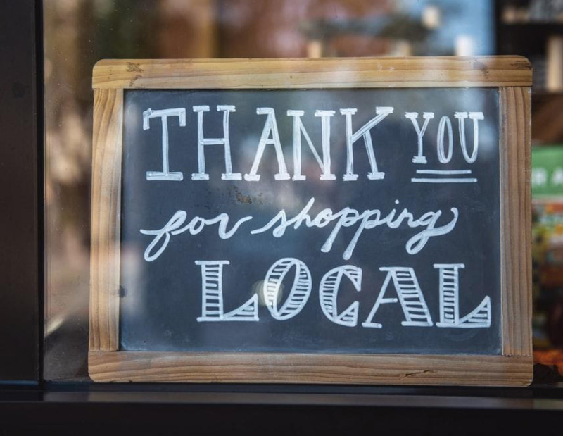 A sign on a small retail business that thanks its customer for shopping locally.